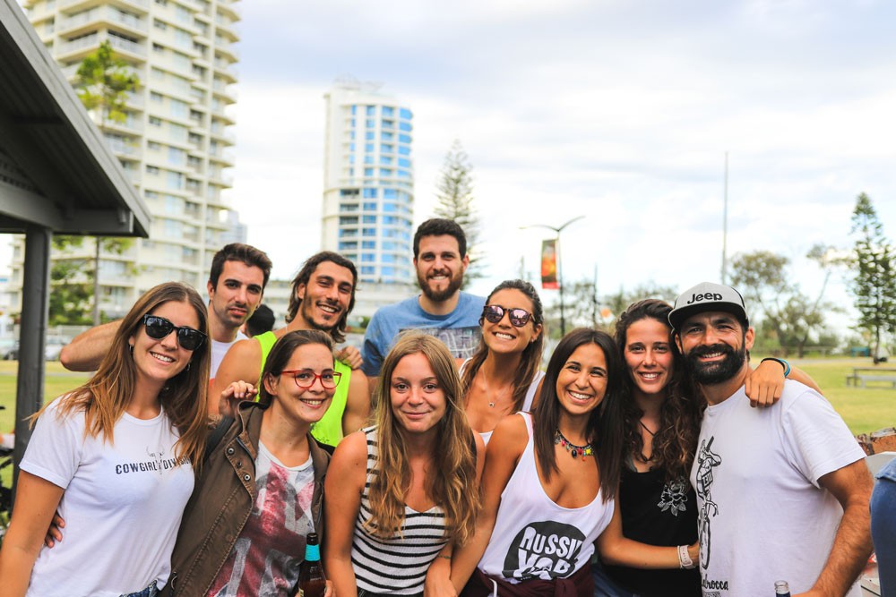 grupo de jóvenes en un círculo riendo y hablando. Detrás se ve el césped y la vegetación